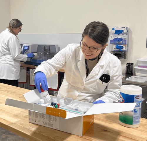 Woman in a lab coat putting bottles into a box