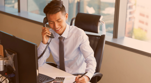 Man looking at paperwork, on the phone, at a computer